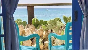 Una habitació amb llit, vistes al mar i cadires turquesa.