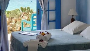 Habitació d'hotel amb un llit, una cadira i vista al mar.