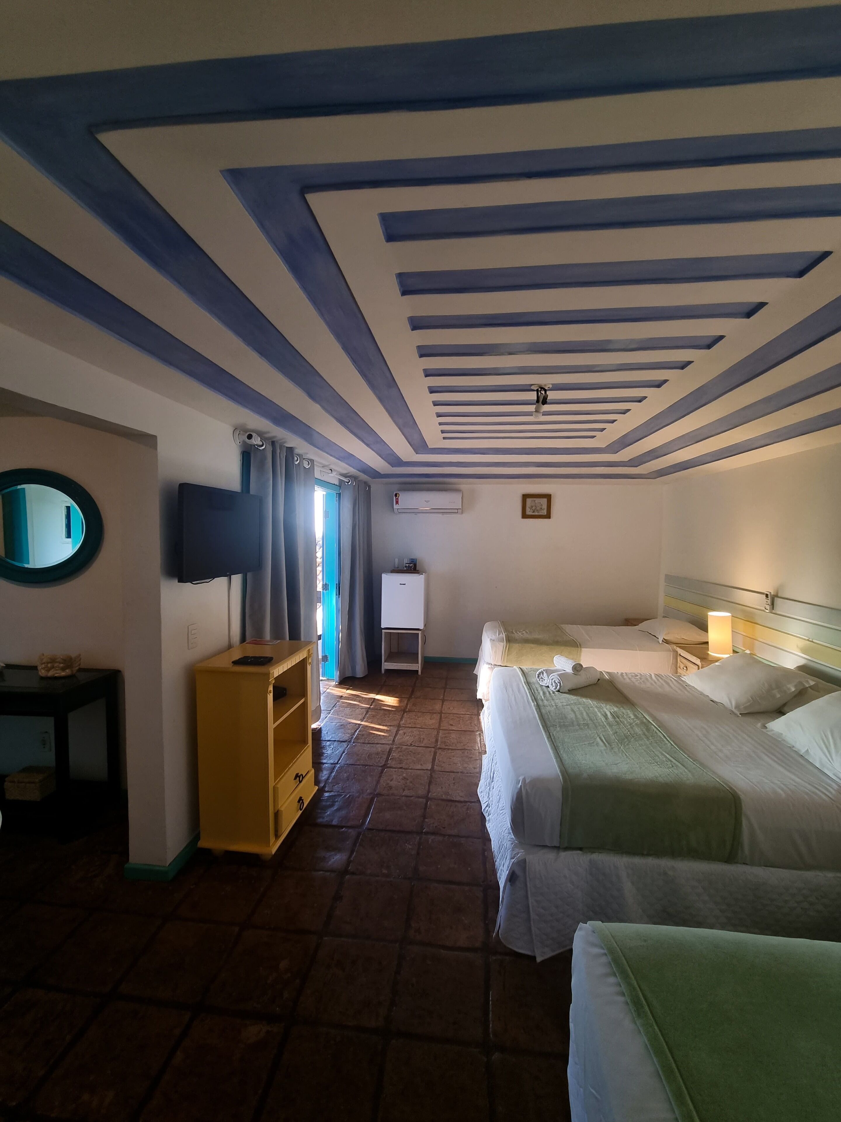 Habitación de hotel con dos camas, televisor, aire acondicionado y un pequeño armario.