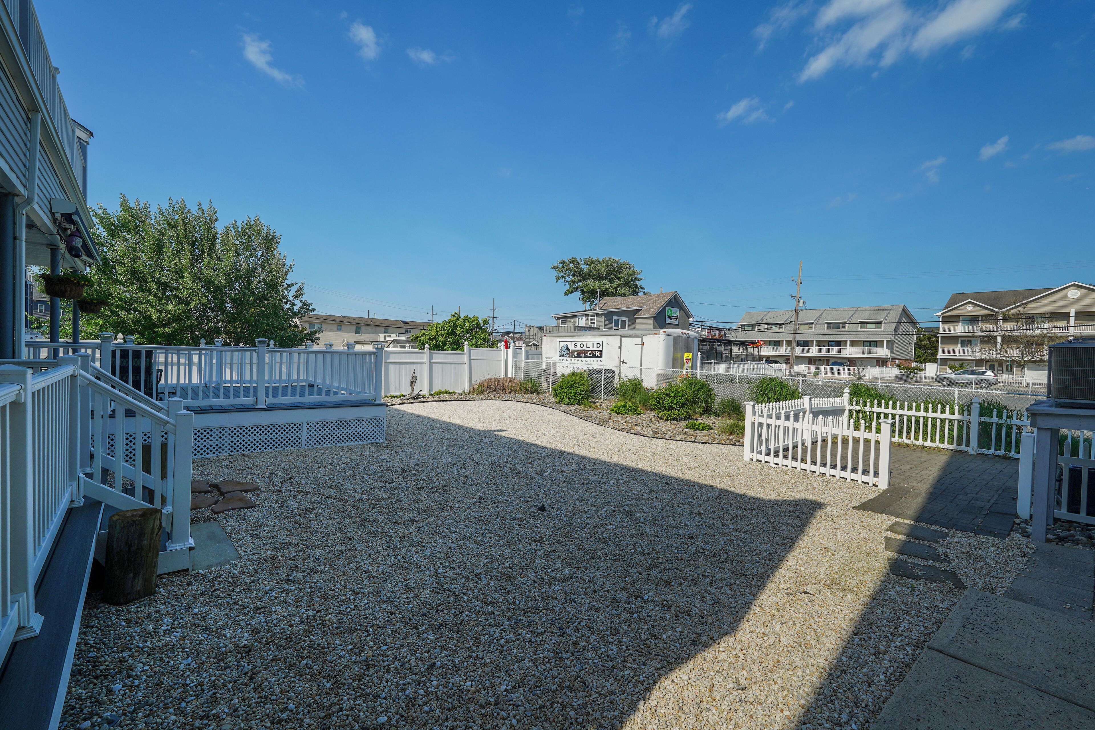 A building with a gravel driveway, white railings, and a fenced area.