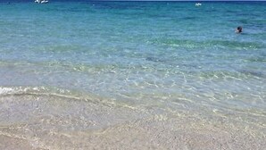 Ein Strand mit klarem Wasser und einer schwimmenden Person.