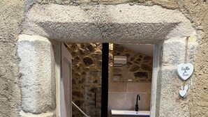 A stone-walled bathroom with a shower, a sink, and a towel rack.