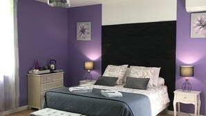 A bedroom with a bed, bedside tables, a dresser, a bench, and a ceiling fan.