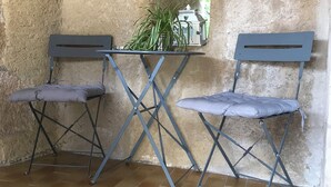 A corner with two foldable chairs, a small table, a potted plant, and a lantern on the wall.