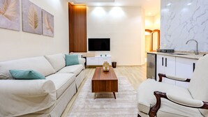 Una sala de estar moderna con sofá, sillón, mesa de centro y una obra de arte en la pared.