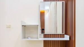 Un baño moderno con pared de paneles de madera, un tocador blanco con espejo y un pequeño estante con una cámara.