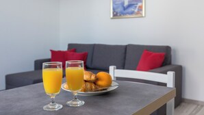 A breakfast table with two glasses of orange juice and a plate of croissants and an orange. - Apartments Oleander Sea View (Konavle)