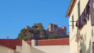 A historic castle on a hill with a red-tiled roof, overlooking a building with laundry hanging outside.