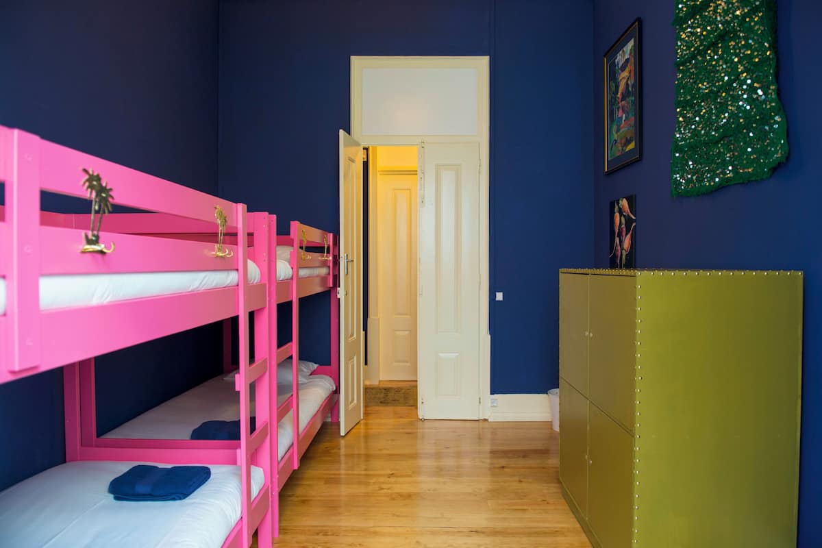 A room with bunk beds, a green cabinet, and a door leading to another room.