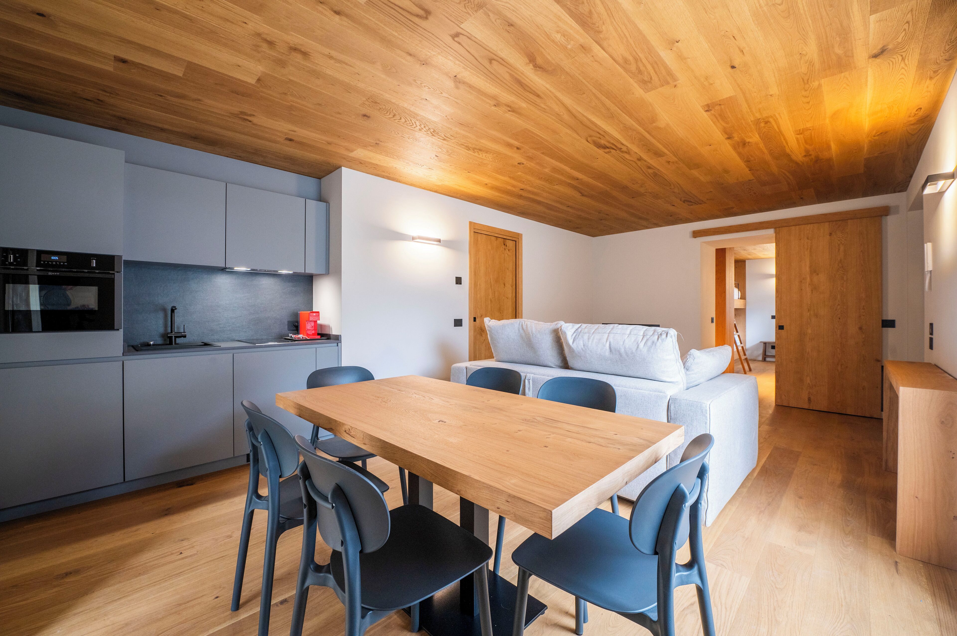 Una cocina moderna con armarios grises, una mesa de comedor de madera y sillas azules.