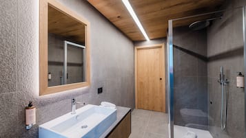 Un baño moderno con un espejo grande, una bañera independiente, un box de ducha y una puerta de madera.