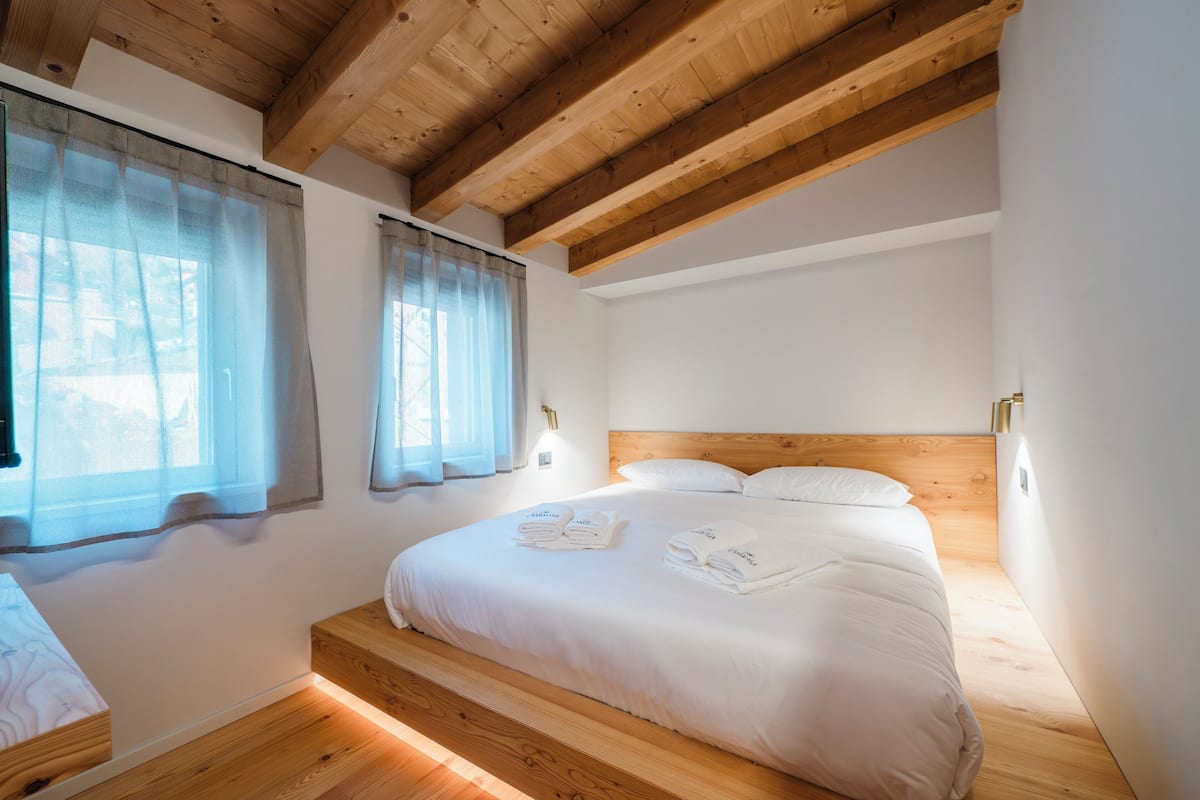 Un dormitorio con cabecera de madera, una cama grande con ropa blanca y dos mesitas de noche.