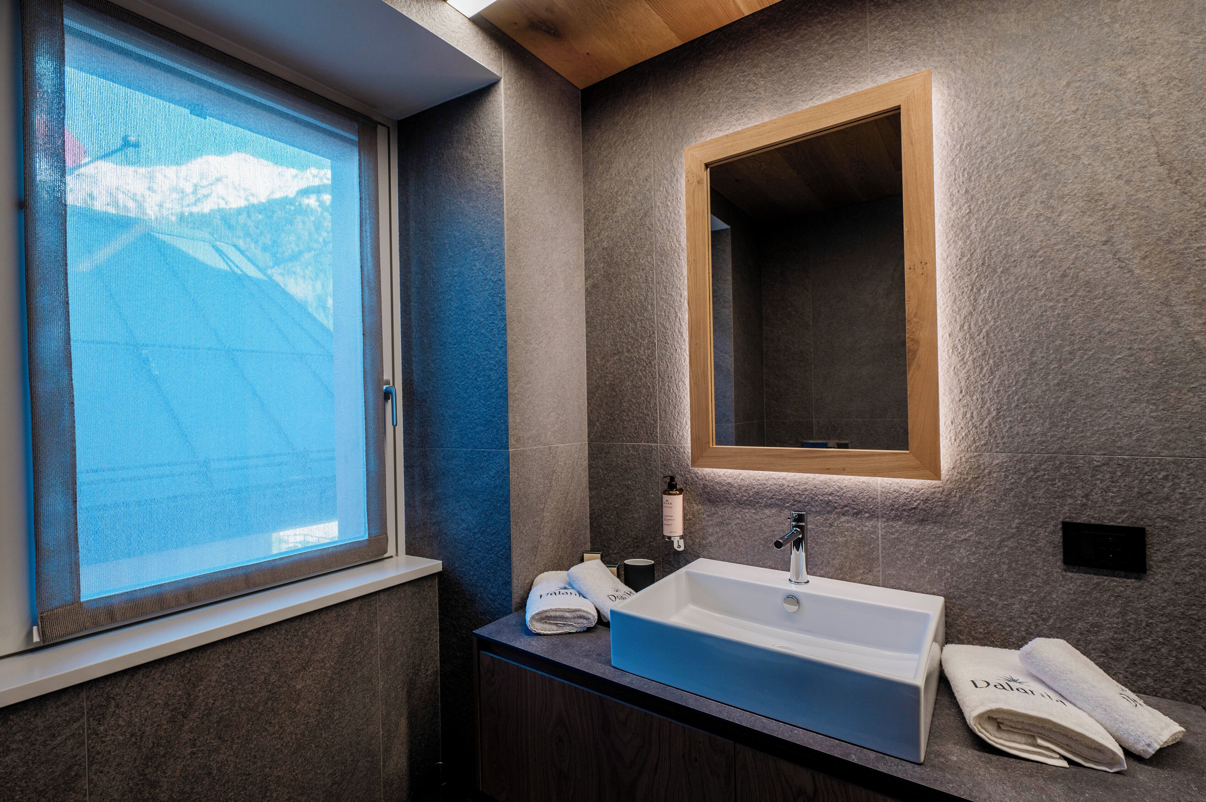 Un baño moderno con un ventanal grande, un lavabo y un espejo.