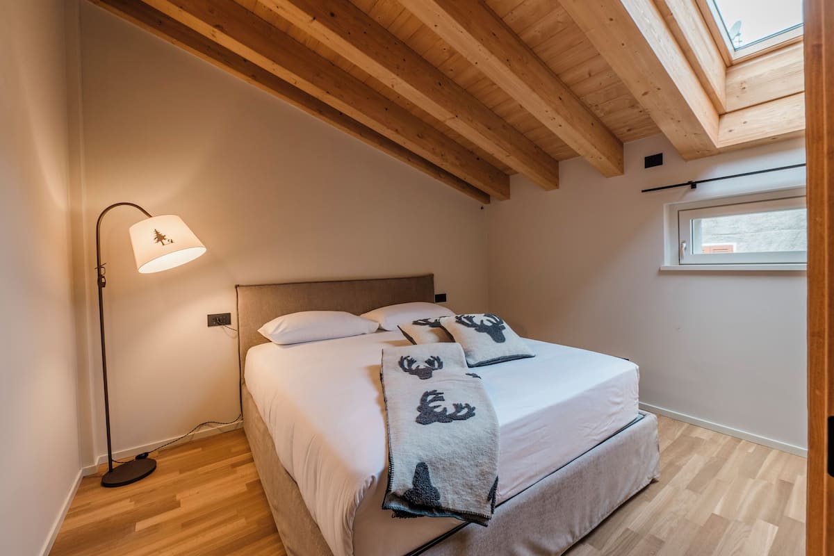 Un dormitorio con cama, una lámpara de pie y un tragaluz.