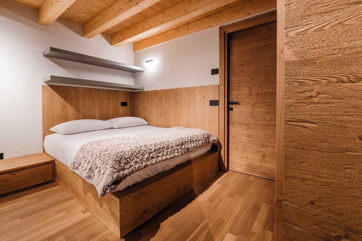 Una cama de madera con cabecera, una mesita de noche y una puerta.