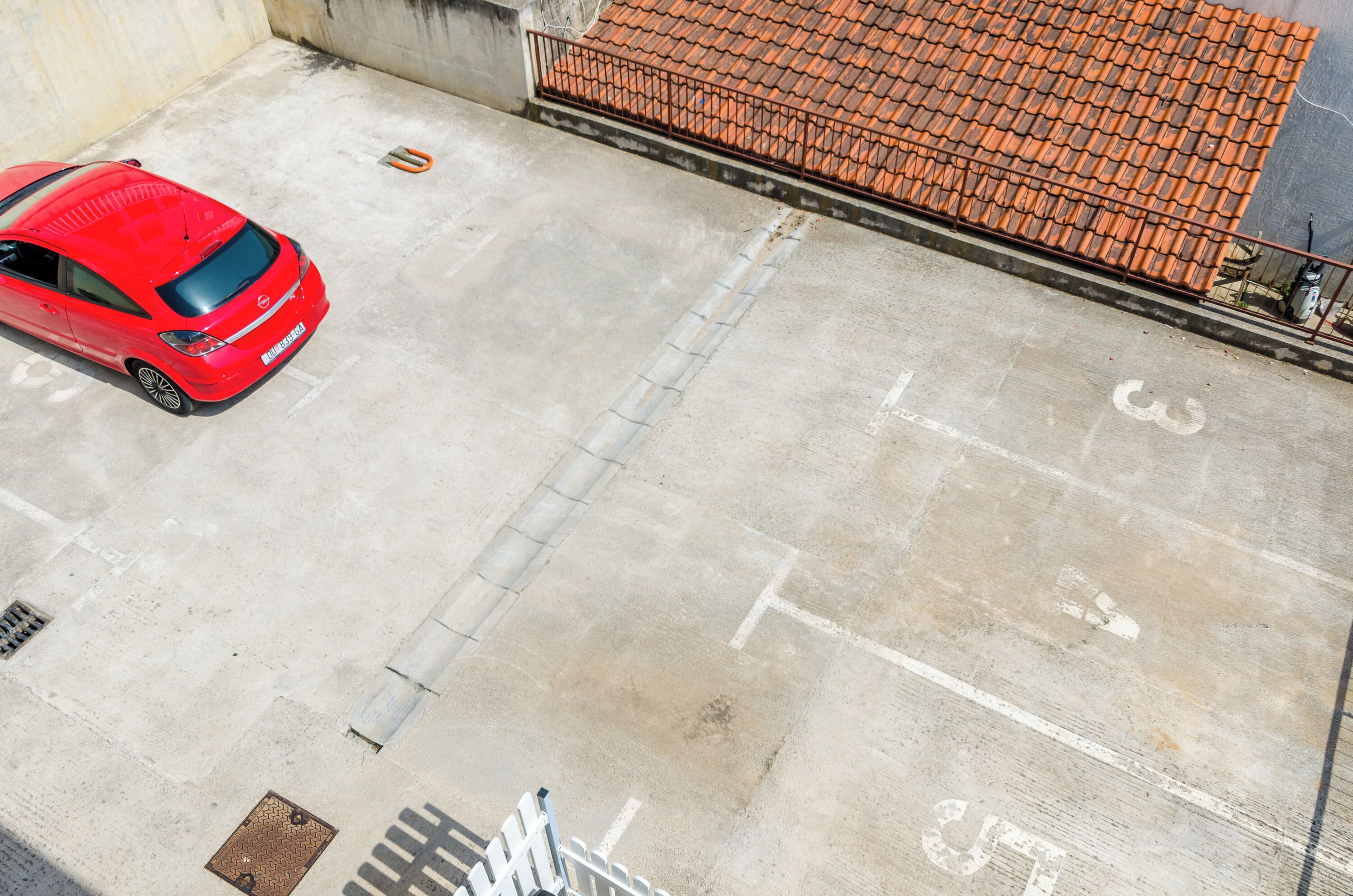 Vue aérienne d’une zone de stationnement avec une voiture rouge garée sur la gauche.