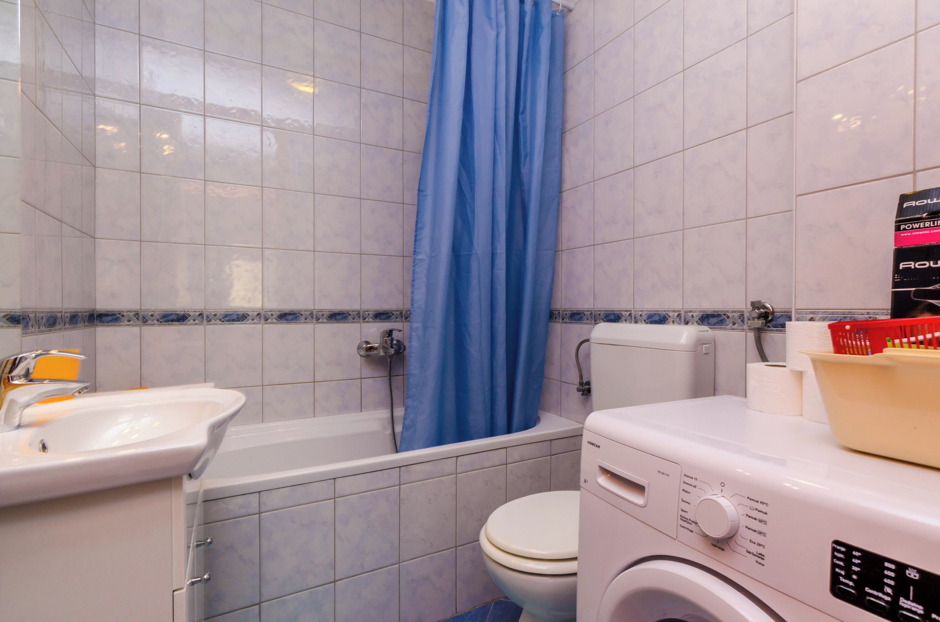 Une salle de bain équipée d’une baignoire, de toilettes et d’un lave-linge.
