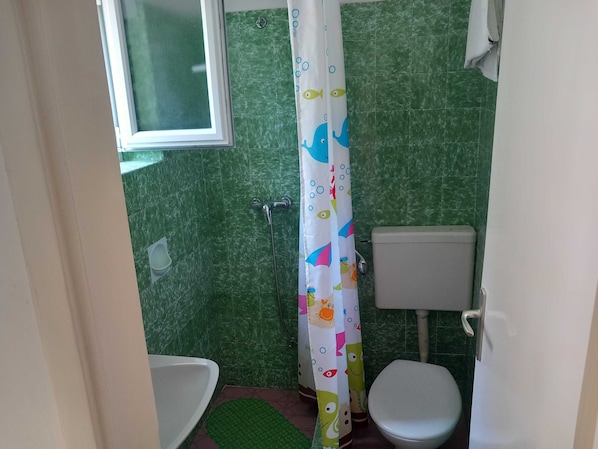 A bathroom with a shower curtain, a toilet, and a sink. - Guest House Mrdalo (Dubrovnik)