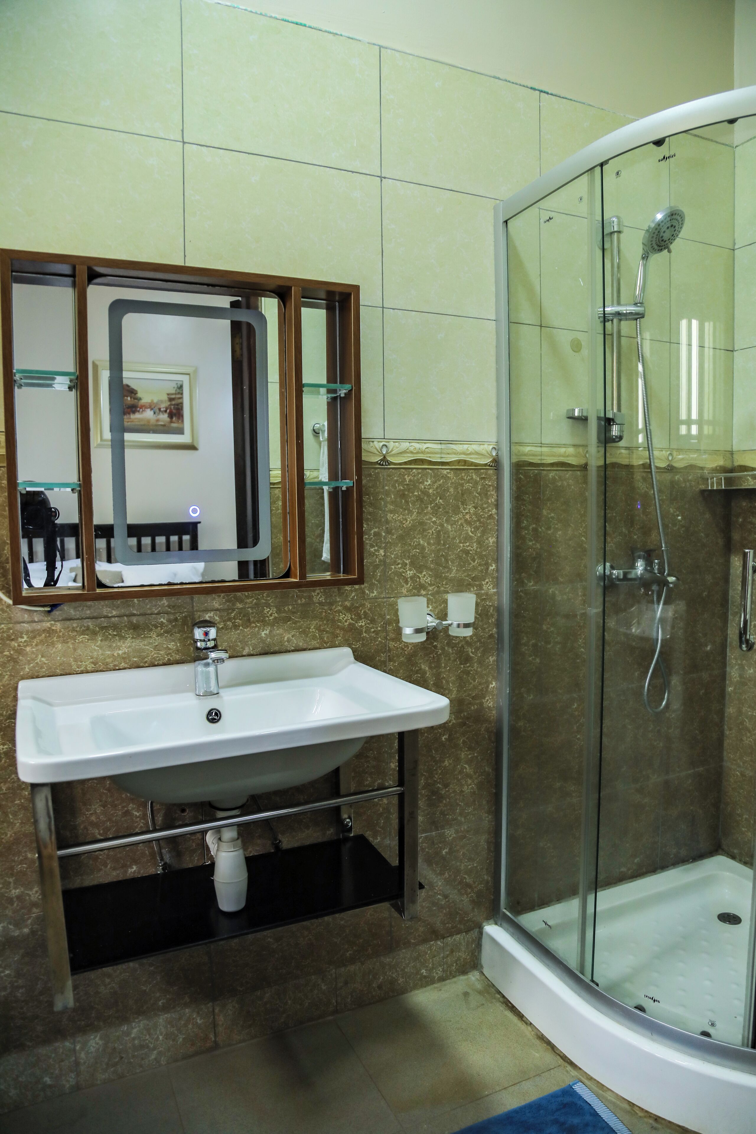A bathroom with a glass-enclosed shower, a white sink, and a mirror with a picture frame.