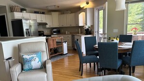 A modern kitchen with white cabinets, a refrigerator, and a dining area with a table and chairs.