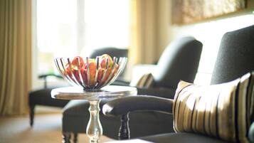 Una mesa de comedor con un frutero y una silla con cojín.