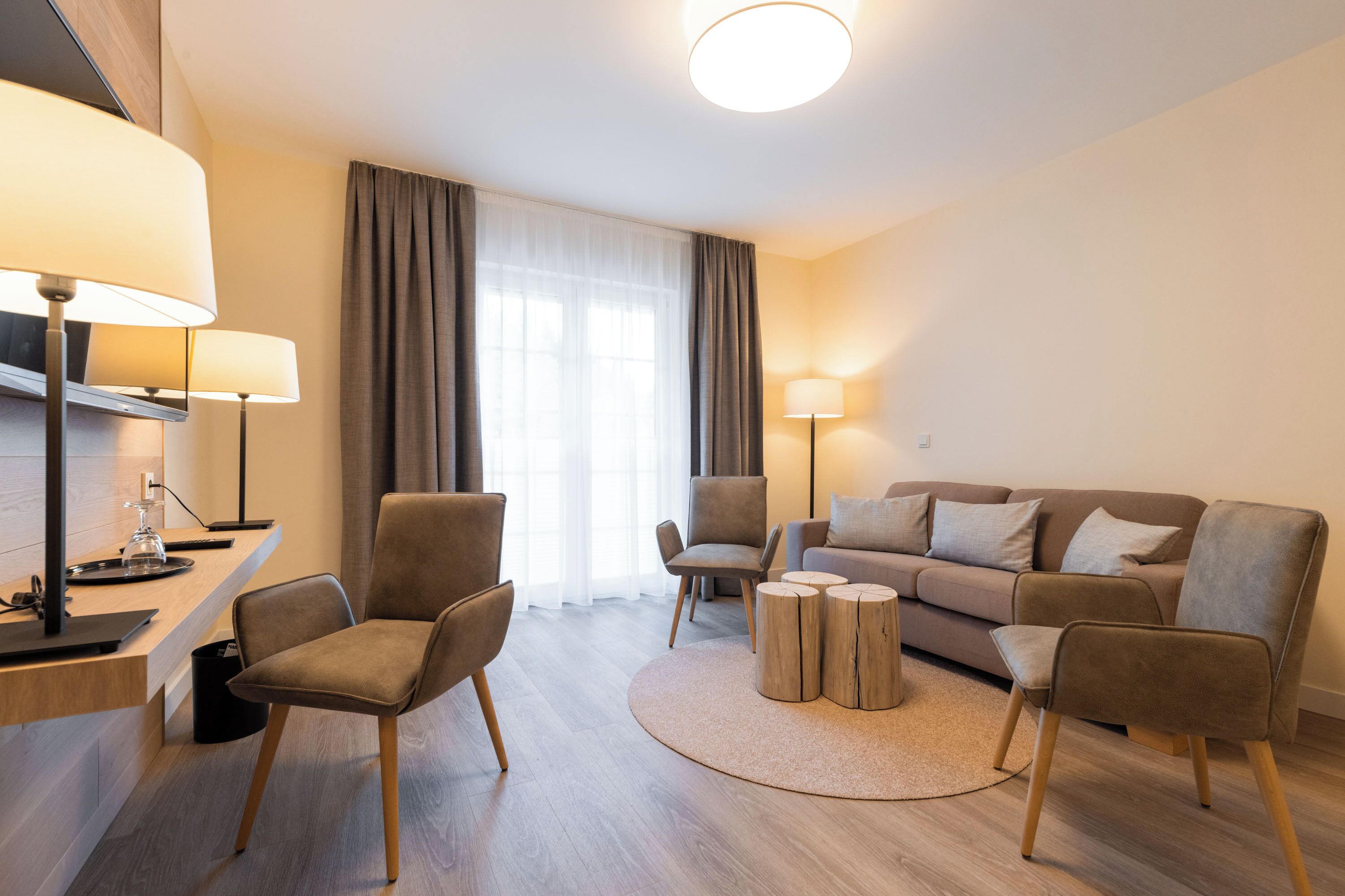 Una sala de estar moderna con un sofá, dos sillones, una mesita de centro y lámparas.