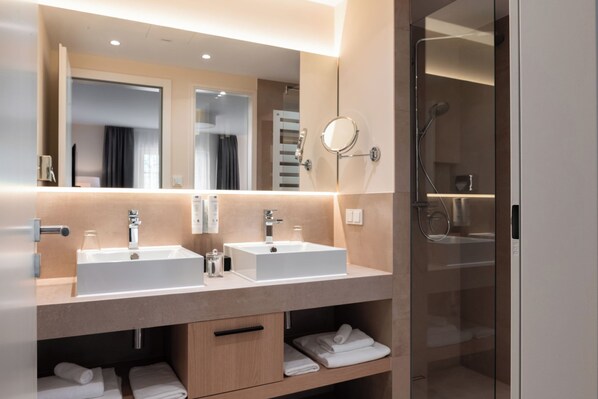 Een moderne badkamer met twee wasbakken, een grote spiegel en een douche met glazen wanden.