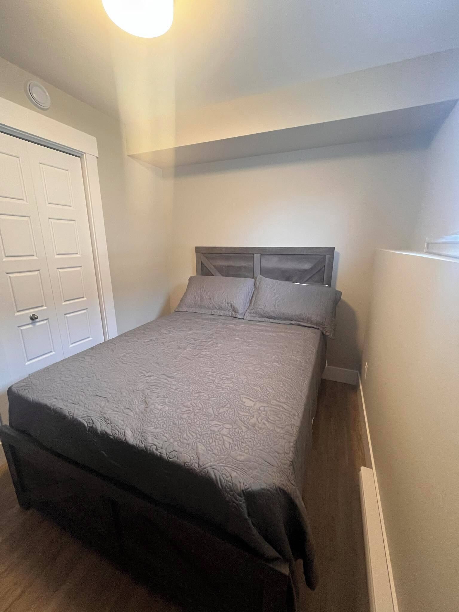 A bedroom with a bed, a wardrobe, and a door.