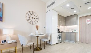 Relax in this stylish room featuring a round clock, flat-screen TV, and compact kitchen area.