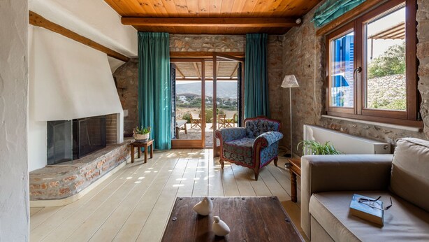 Una sala de estar acogedora con chimenea, un sofá, una silla y vistas al exterior.