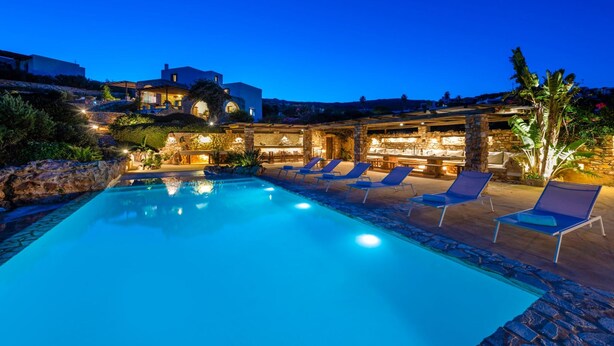 A swimming pool with lounge chairs, stone walls, and a bar area with stone arches. - Blue Greens Villas in Krios, Paros Island (Paros)