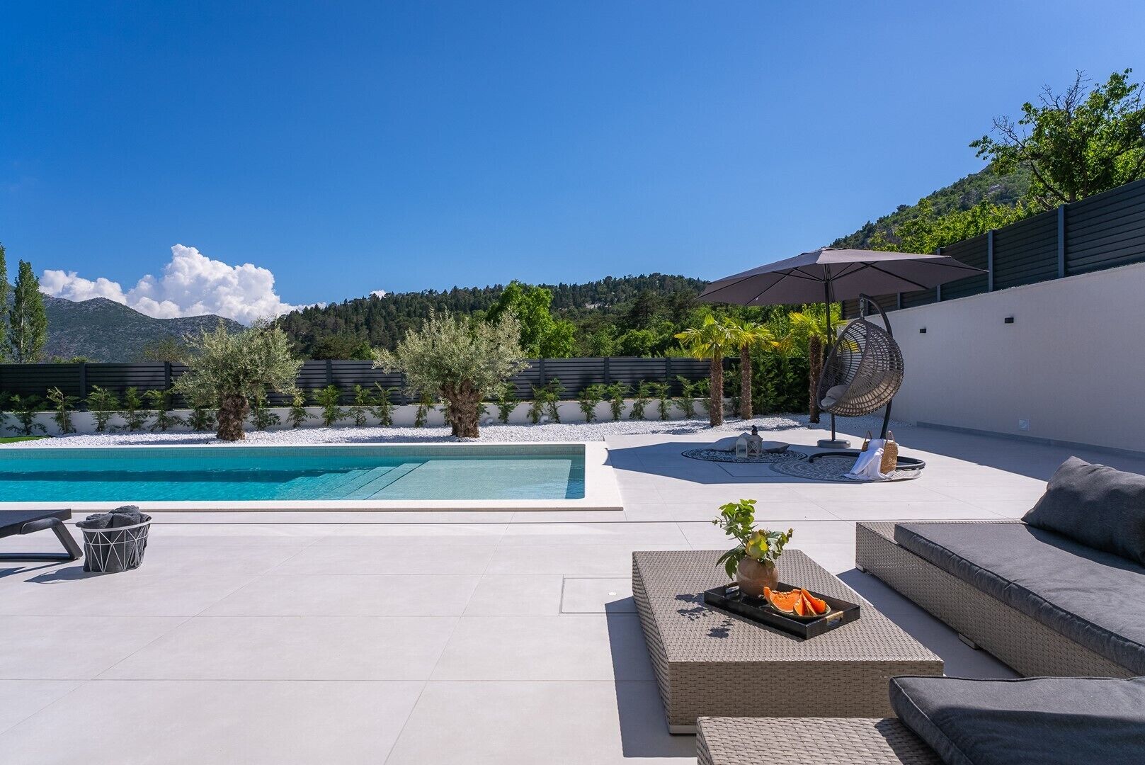 A modern outdoor patio with a pool, seating areas, and a fan.