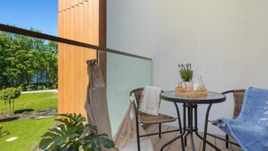 Un balcón con una mesa, sillas y vista a un jardín.