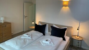 A hotel room with a bed, two bedside tables, a dresser, and a wall-mounted light fixture. - Design-ferienwohnung Altstadtperle Mitten im Zentrum von Hildburghausen (Hildburghausen)