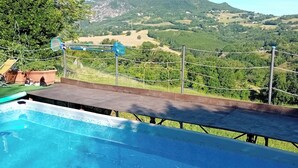 Une piscine avec vue sur un paysage montagneux et un espace clos comprenant un court de tennis.