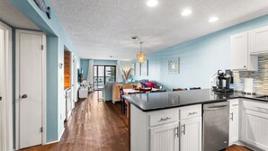 A spacious kitchen with white cabinetry, a black countertop, and a dining area with a table and chairs.
