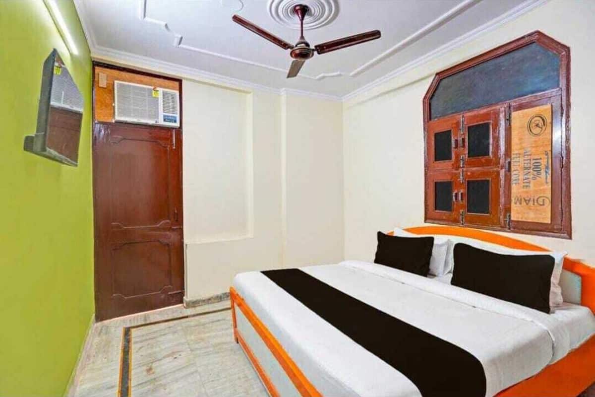 A bedroom with a bed, a ceiling fan, a wooden door, and a window with a wooden frame.