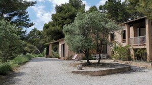 A rustic building with a gravel driveway, outdoor seating, and a tree in front. - Maison Familiale à Aix en Provence, au Calme, vue Magnifique (Aix-en-Provence)