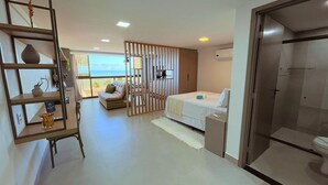 Ein Hotelzimmer mit Bett, Sofa, Schreibtisch, Bücherregal und Meerblick.