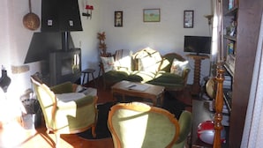 Una sala de estar acogedora con chimenea, mobiliario tapizado en verde y techo de madera.