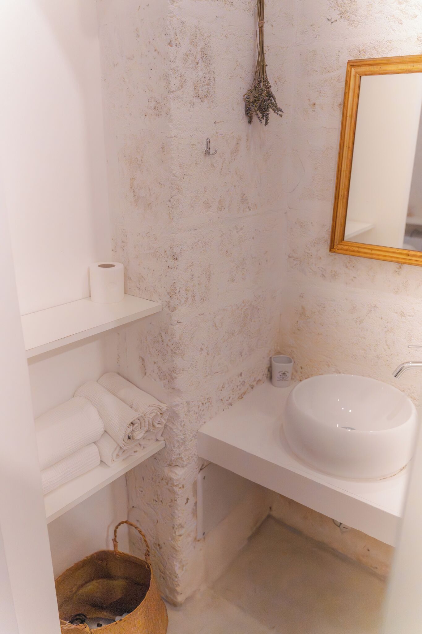 Une salle de bain avec un lavabo blanc, un miroir, un porte-serviettes et un petit panier.