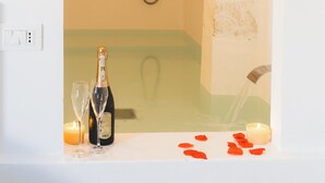 A bathroom with a shower, a bottle of champagne, two glasses, and rose petals on the counter. - Corte Mercurio Beb (Ugento)