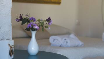 Een witte vaas met paarse bloemen op een tafel in een hotelkamer.