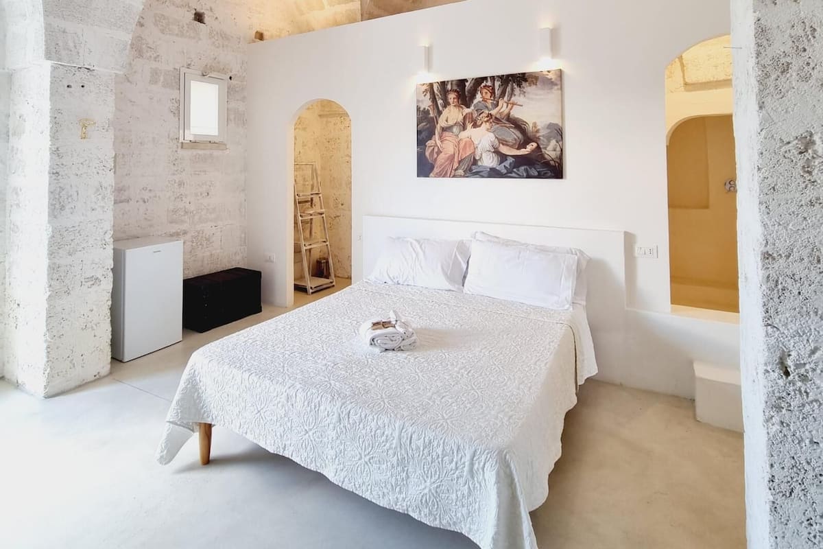 Un dormitorio con una cama grande, un cuadro en la pared y un techo de piedra.