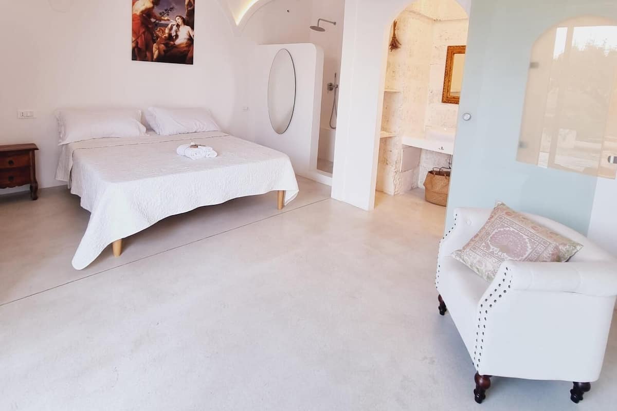Un dormitorio amplio con una cama grande, un tocador con espejo y vistas a un techo de piedra rústica.