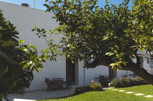 Un edificio blanco con un patio amoblado, incluyendo mobiliario exterior y un árbol.