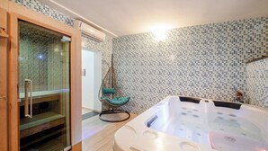 A modern bathroom with a glass-enclosed shower, a wooden cabinet, a hanging chair, and a large bathtub. - Hotel Solcalante (Procida)