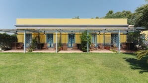 A yellow building with a covered patio area, featuring outdoor seating and a small garden. - Hotel Solcalante (Procida)