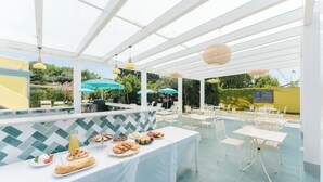 An outdoor dining area with a white table, chairs, and umbrellas. - Hotel Solcalante (Procida)