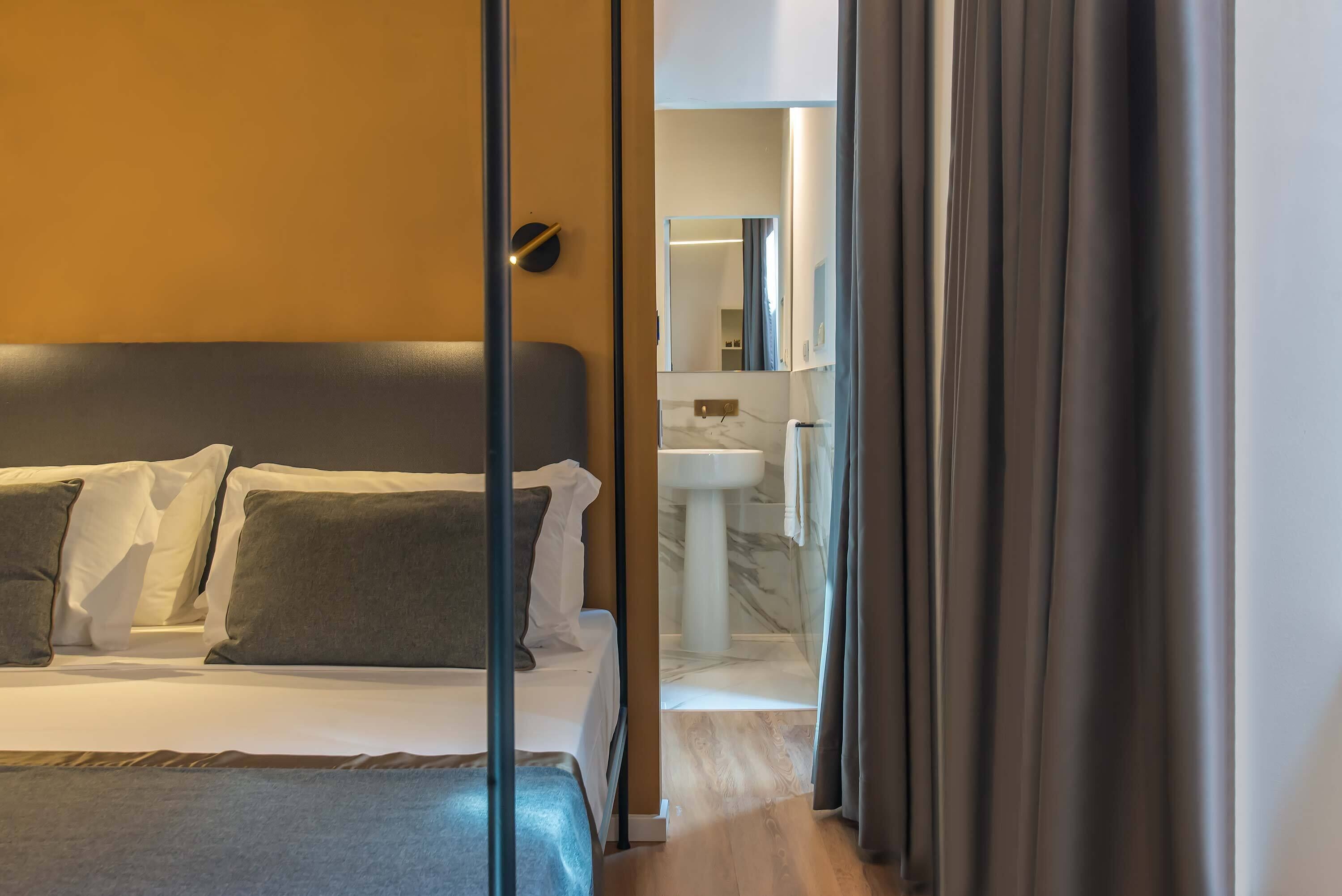 A modern hotel room with a bed, a bedside table, and a view of the bathroom.